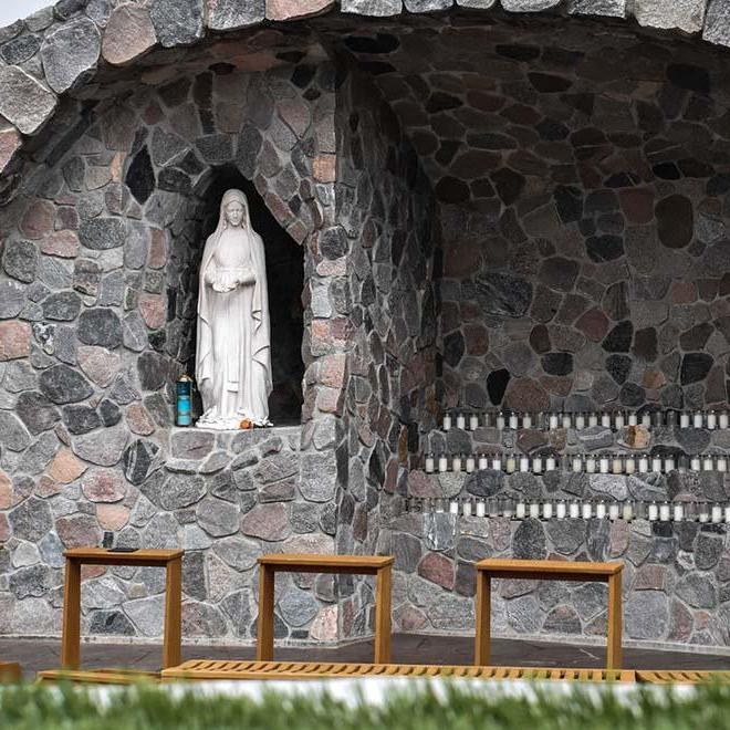 A closeup of grotto with candles and statue of Mary