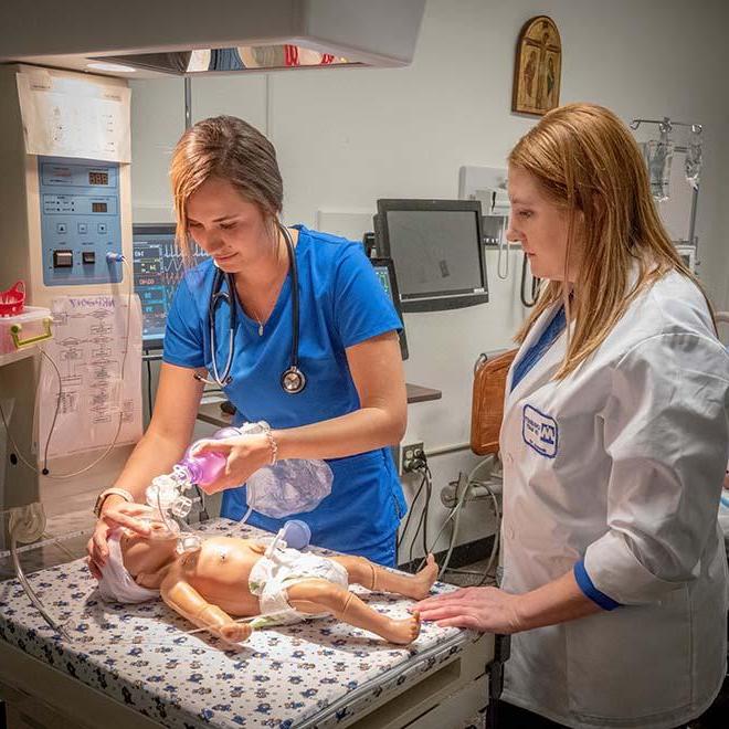 在模拟实验室里，实习护士在教授的监督下给婴儿模型输氧
